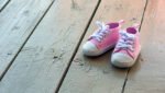 Pink baby girl shoes on a wooden floor outdoors