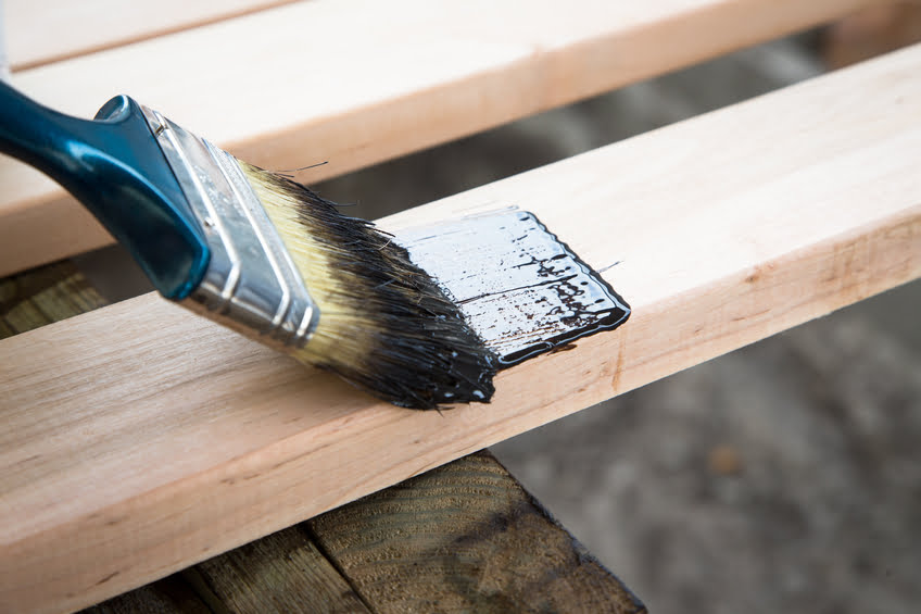 Varnishing natural wood with paint brush. Wood texture and paintbrush - housework background