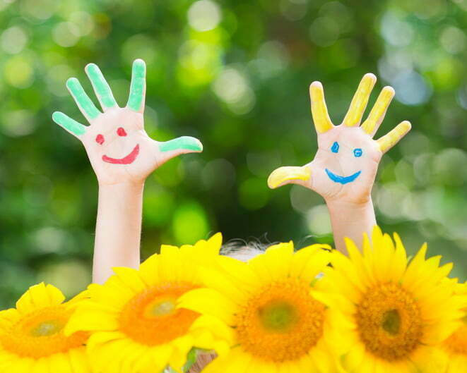 Happy child with smiley on hands against green spring background