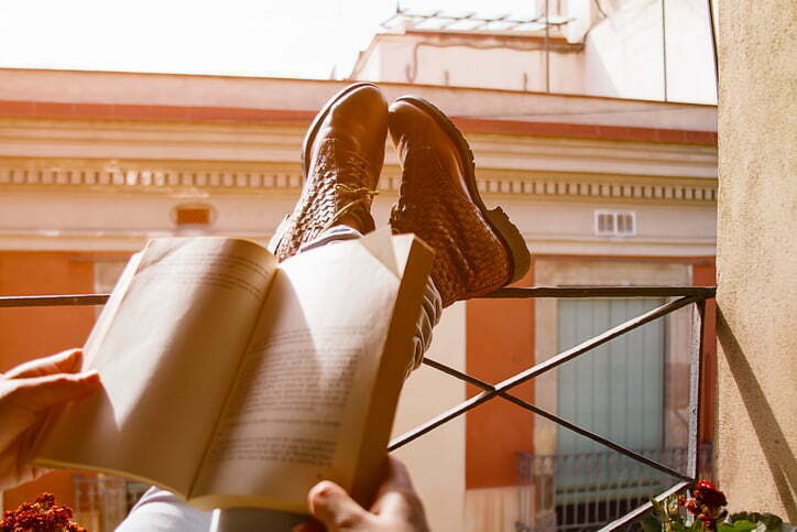 Women legs reading a book in the balcony with the sunset light