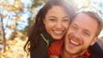Backlit portrait of mixed race couple embracing in a forest