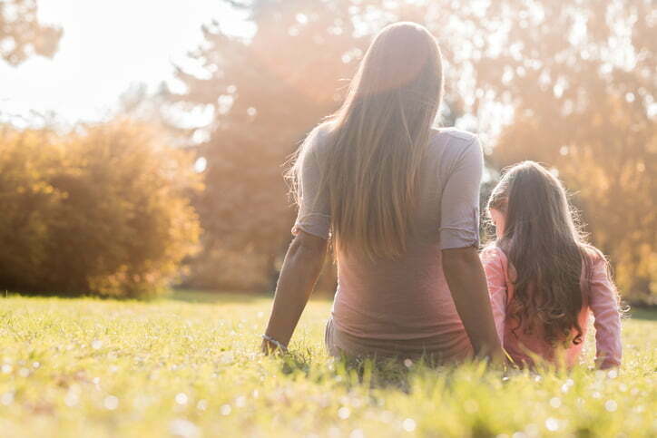 mom and daughter are relaxing on the grass and looking a way
