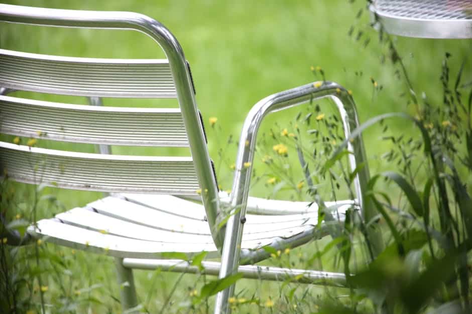 Powder-coated aluminum patio chair with visible UV and salt-air corrosion on the frame joints in a Florida backyard